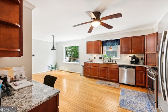 kitchen featuring ornamental molding, sink, decorative light fixtures, light wood-type flooring, and appliances with stainless steel finishes