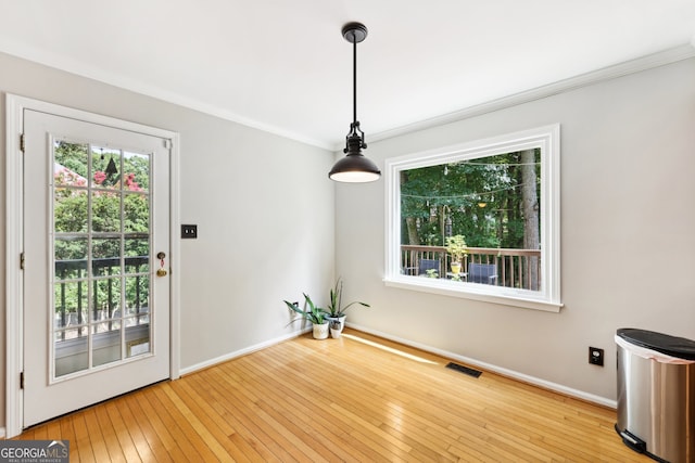 unfurnished dining area with light hardwood / wood-style floors and crown molding