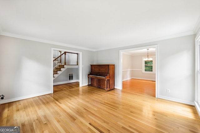 unfurnished living room with crown molding, a notable chandelier, and wood-type flooring