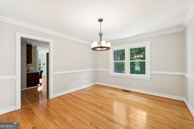 spare room featuring ornamental molding, a notable chandelier, and wood-type flooring