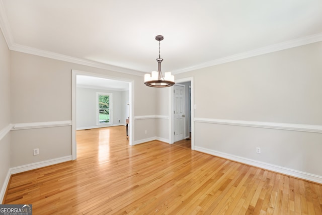 unfurnished dining area featuring a chandelier, crown molding, and light wood-type flooring