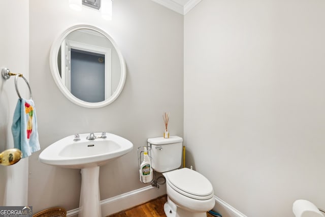 bathroom with crown molding, hardwood / wood-style flooring, and toilet