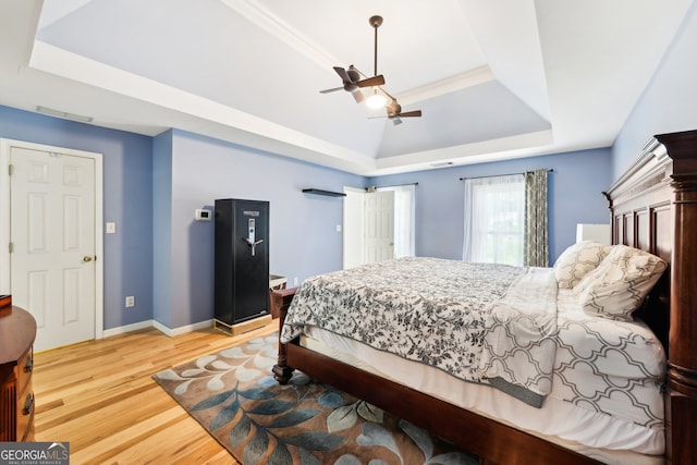 bedroom featuring ceiling fan, hardwood / wood-style flooring, and a raised ceiling