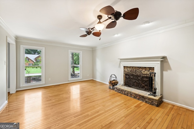 unfurnished living room featuring light hardwood / wood-style floors, crown molding, a stone fireplace, and ceiling fan