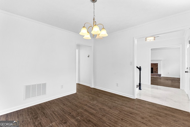 spare room with a chandelier, crown molding, and dark hardwood / wood-style flooring