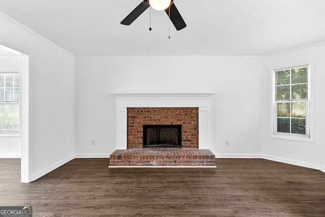 unfurnished living room with crown molding, dark wood-type flooring, a fireplace, and ceiling fan