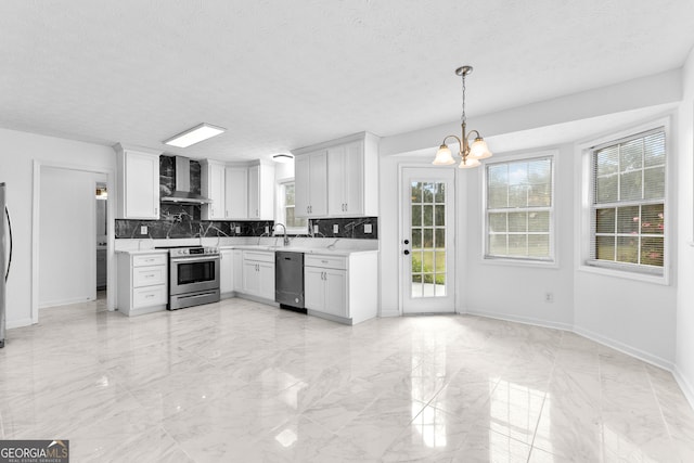 kitchen featuring decorative backsplash, white cabinets, an inviting chandelier, wall chimney exhaust hood, and stainless steel appliances