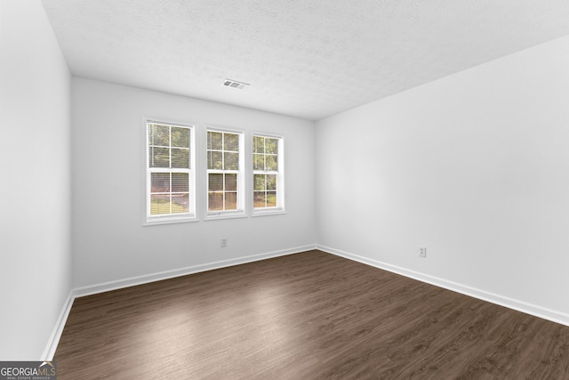 unfurnished room with a textured ceiling and dark hardwood / wood-style flooring