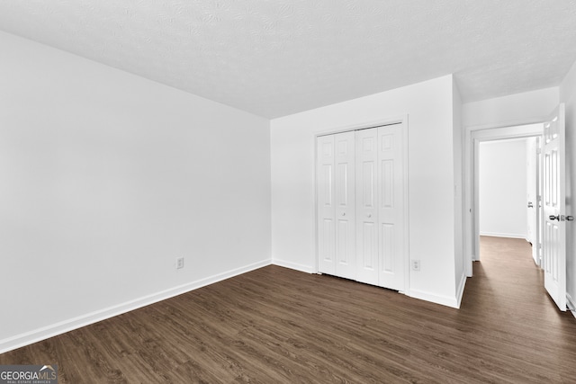 unfurnished bedroom featuring a closet, dark hardwood / wood-style floors, and a textured ceiling