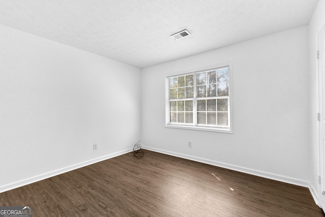 spare room with a textured ceiling and dark wood-type flooring