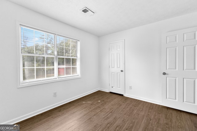 spare room featuring a textured ceiling and dark wood-type flooring