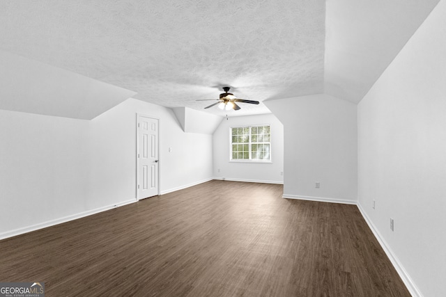 bonus room with lofted ceiling, a textured ceiling, dark wood-type flooring, and ceiling fan