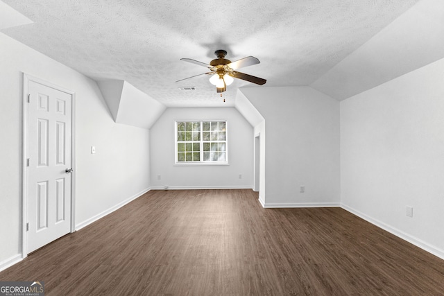 bonus room featuring ceiling fan, a textured ceiling, lofted ceiling, and dark hardwood / wood-style floors