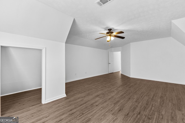 additional living space featuring lofted ceiling, a textured ceiling, dark wood-type flooring, and ceiling fan