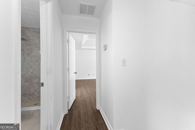 hallway with a textured ceiling and dark hardwood / wood-style floors