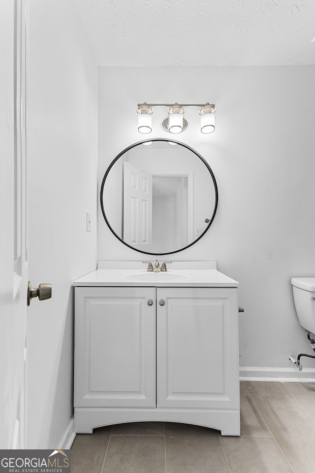 bathroom featuring toilet, a textured ceiling, vanity, and tile patterned flooring