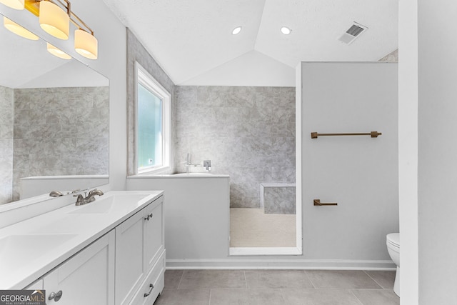 bathroom with a textured ceiling, toilet, tile patterned floors, vaulted ceiling, and vanity