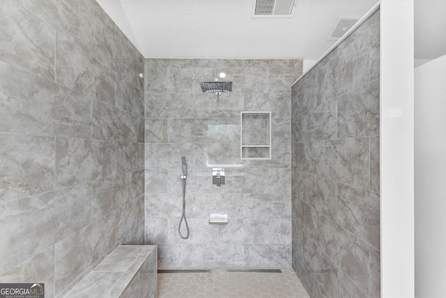 bathroom with tiled shower and a textured ceiling