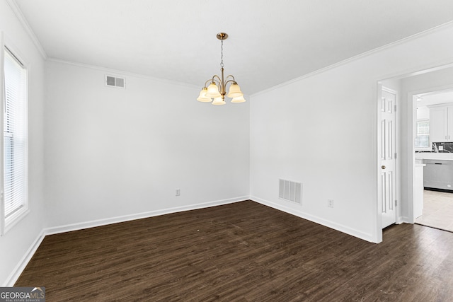 spare room featuring crown molding, a notable chandelier, dark hardwood / wood-style flooring, and plenty of natural light