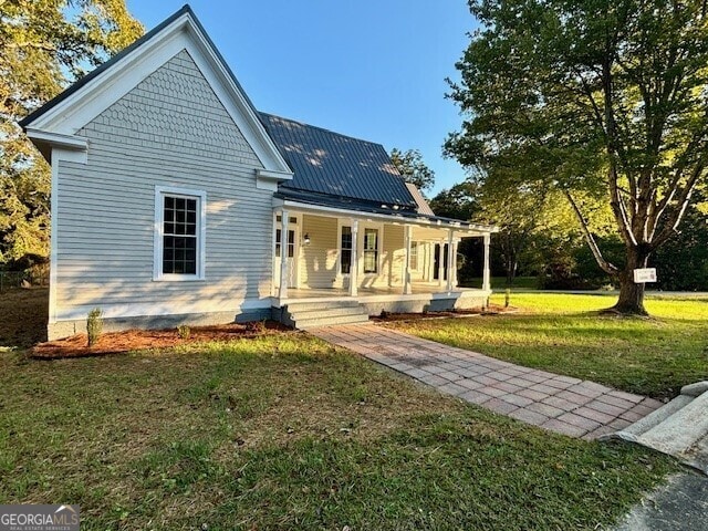 back of house featuring covered porch and a yard