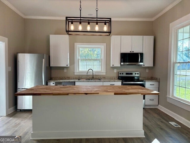 17843 Main St, Woodbury, GA 30293 - kitchen featuring appliances with stainless steel finishes, white cabinets, wooden counters, and decorative light fixtures