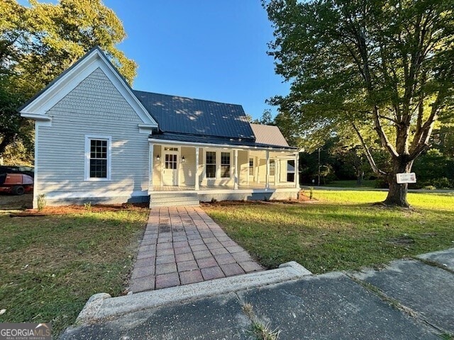 back of property with covered porch and a lawn