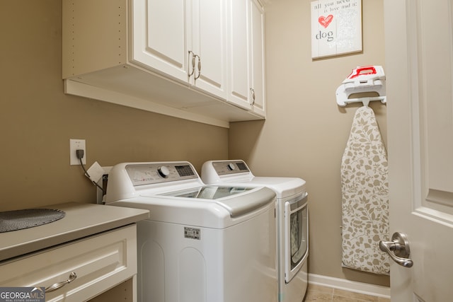 clothes washing area featuring washing machine and dryer, light tile patterned floors, and cabinets