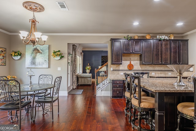 kitchen with dark brown cabinetry, crown molding, light stone countertops, and dark hardwood / wood-style flooring