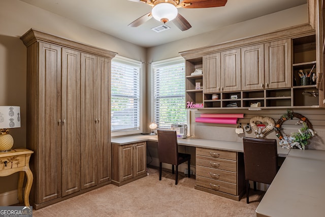 carpeted office space featuring built in desk and ceiling fan