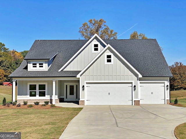 view of front of home with covered porch, a front lawn, and a garage