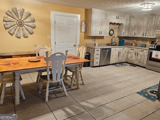 kitchen with sink, appliances with stainless steel finishes, a textured ceiling, and light tile patterned floors