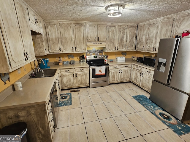 kitchen featuring light brown cabinetry, a textured ceiling, appliances with stainless steel finishes, and sink