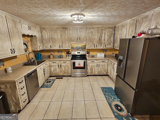 kitchen featuring sink, a textured ceiling, stainless steel appliances, light tile patterned floors, and light brown cabinets