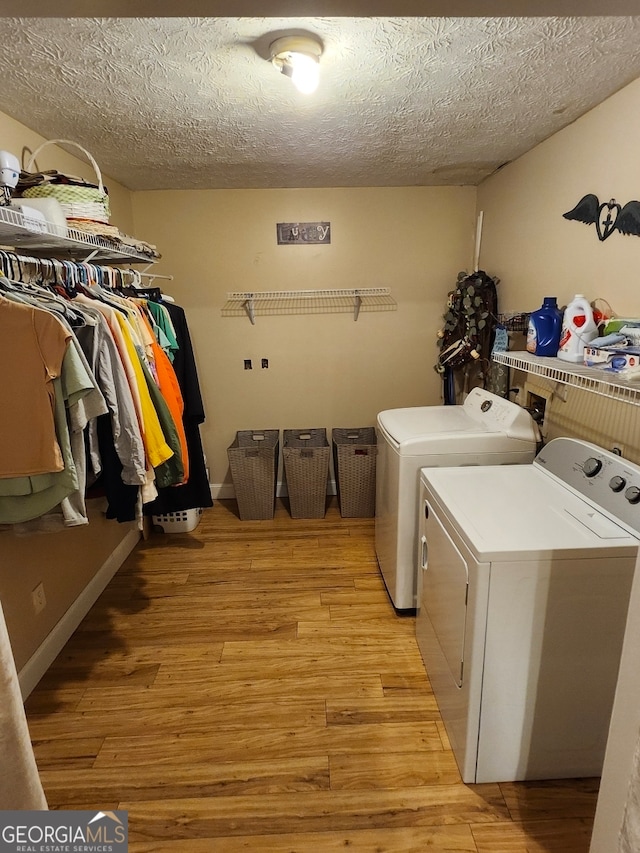 washroom featuring a textured ceiling, light hardwood / wood-style flooring, and washer and clothes dryer