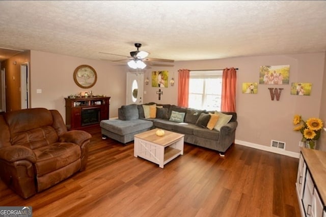 living room with a textured ceiling, wood-type flooring, and ceiling fan