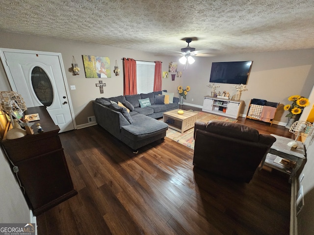 living room with a textured ceiling, dark wood-type flooring, and ceiling fan