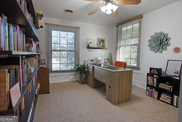 carpeted home office with ceiling fan and a wealth of natural light