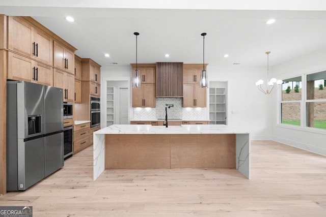 kitchen with decorative backsplash, light stone countertops, light hardwood / wood-style floors, a notable chandelier, and stainless steel appliances