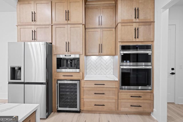 kitchen with light brown cabinets, wine cooler, backsplash, light hardwood / wood-style flooring, and stainless steel appliances