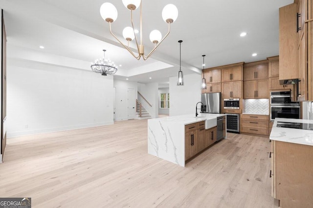 kitchen with a large island, sink, decorative light fixtures, and light hardwood / wood-style floors