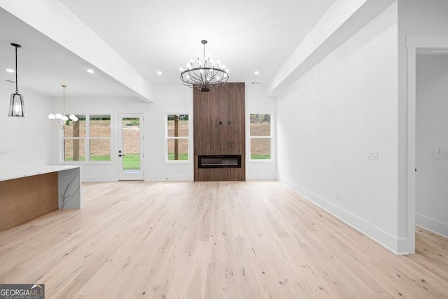 unfurnished living room featuring light hardwood / wood-style floors, a chandelier, and a large fireplace