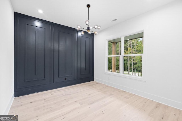 unfurnished dining area featuring light hardwood / wood-style floors and a notable chandelier