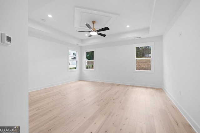 spare room featuring light hardwood / wood-style floors, a tray ceiling, and ceiling fan