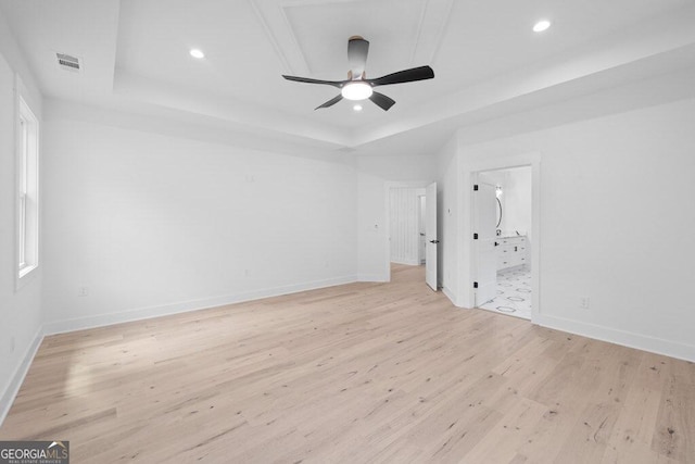 unfurnished room with a tray ceiling, light hardwood / wood-style floors, and ceiling fan