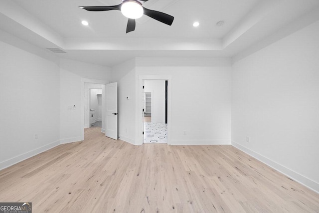 unfurnished bedroom featuring light hardwood / wood-style flooring, a tray ceiling, and ceiling fan