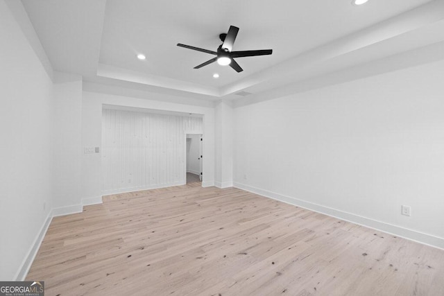 unfurnished room with a tray ceiling, light hardwood / wood-style floors, and ceiling fan