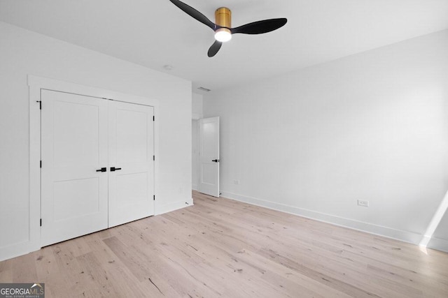 unfurnished bedroom featuring a closet, light hardwood / wood-style floors, and ceiling fan