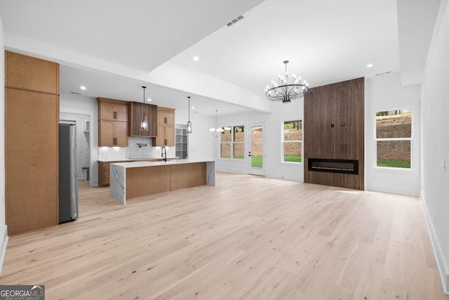 kitchen featuring a spacious island, light wood-type flooring, and pendant lighting