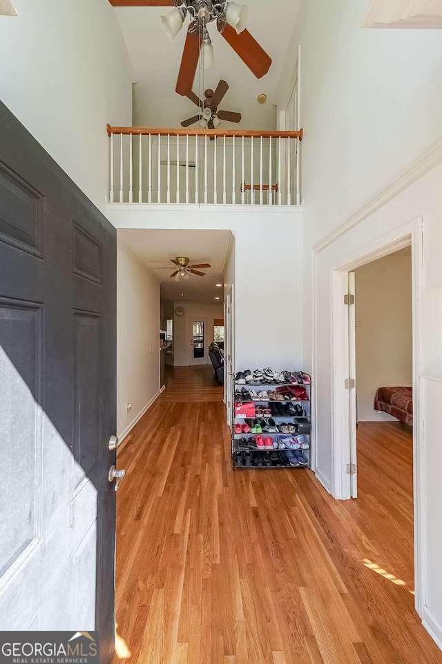 foyer with wood-type flooring, a towering ceiling, and ceiling fan