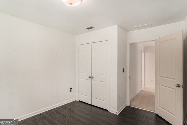 unfurnished bedroom with dark wood-type flooring and a closet